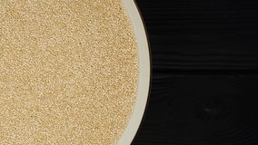 superfood quinoa seeds in white plate rotating top view. dark wooden background. place for text