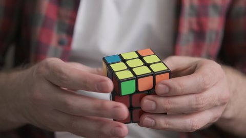 BELARUS, MINSK - MAY 23, 2020: Mans hands solving rubik cube. Rubik's cube in the hands of man. Puzzle cube. Close-up. Famous toy