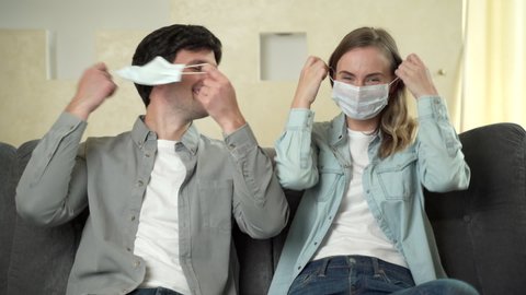 The Covid-19 virus epidemic ends, a woman and a man sitting on a sofa at home take off their surgical masks