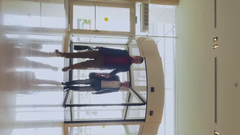 Vertical view of people walking through revolving door in modern business center or shopping mall. Interior of modern stylish hall in hotel or office building with
