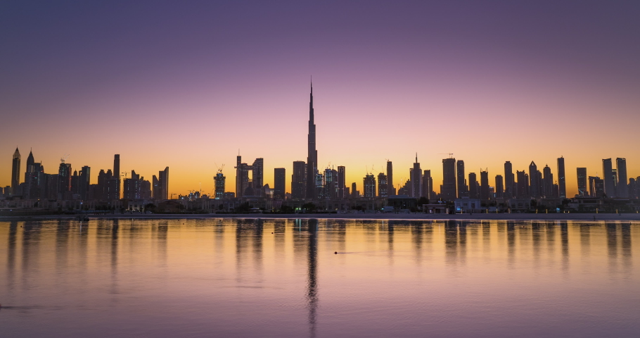 Sunrise in Dubai hyper lapse or time lapse view from boat or sea. The Sun rises over UAE skyscrapers at morning. Camera moves along beach, coast, shore Royalty-Free Stock Footage #1053445856
