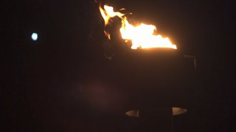 Natural gas flare burning in slow motion near a crude oil rig during the night. Subtle left to right cameraement.