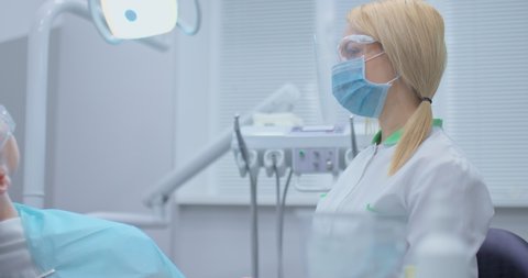 Professional dentist takes a boron machine and starts drilling a tooth from a patient, treating tooth decay. Treatment of toothache in a patient in a modern dental clinic, modern equipment.