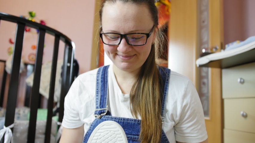 Happy Girl sits on a floor holds one new white sneaker in his hands.