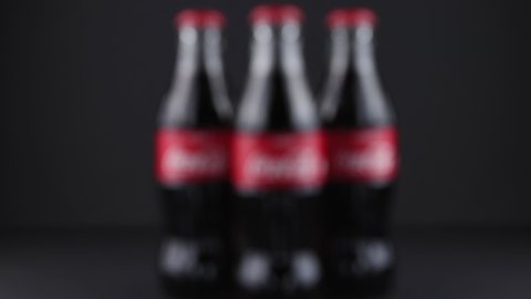 Minsk, Belarus, 05.2020 defocused silhouettes with three glass bottles of coca-cola classic. camera shaking effect and black background