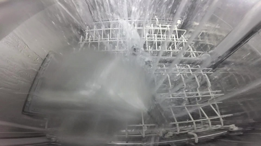 Slow motion. The master repairs the dishwasher and checks the operation of the nozzle mechanism, which rotates and sprays water. The process inside the dishwasher. Inside view of a dishwasher. | Shutterstock HD Video #1053468416