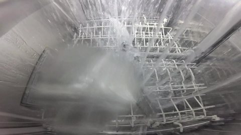 Slow motion. The master repairs the dishwasher and checks the operation of the nozzle mechanism, which rotates and sprays water. The process inside the dishwasher. Inside view of a dishwasher.