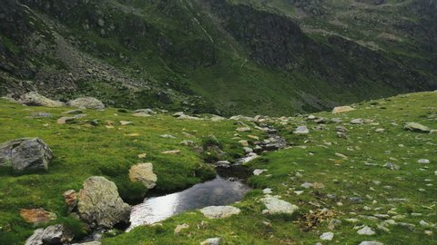 Rocky mountain stream at the green plain. Pyrenees, Andorra, 2020