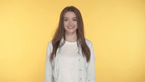 Smiling young woman looking at the camera. Yellow background.