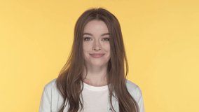 Close-up portrait of young woman showing OK gesture. Slowmotion. Yellow background.