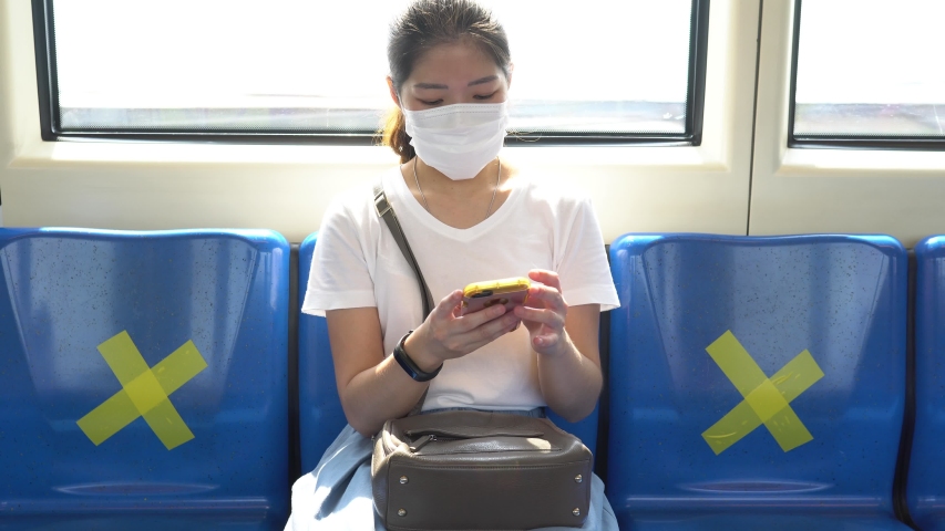young asian woman wearing face mask sitting in the metro train and keep social distancing to prevent covid-19 or coronavirus infection. new normal lifestyle concept Royalty-Free Stock Footage #1053481154