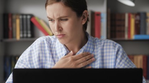 Trouble breathing, chest pain. Close-up woman working at computer, she has difficulty breathing or pain in chest touches chest with her hand. Panic attack, asthma, osteochondrosis concepts