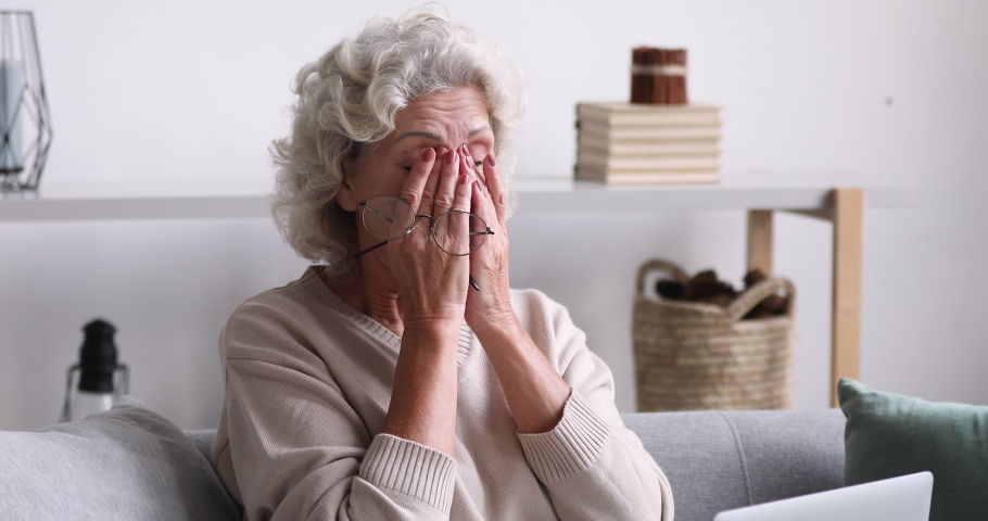 Unhealthy middle aged 60s retired woman massaging nose bridge, feeling eyes tension due to computer overwork at home. Upset mature older grandmother suffering from blurred eyesight using laptop. Royalty-Free Stock Footage #1053484505