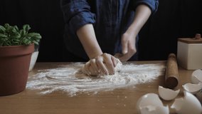 Woman kneads yeast dough with her hands at home in the kitchen on the table to make bread or pita. Video taken close-up from a tripod with natural light in 4k