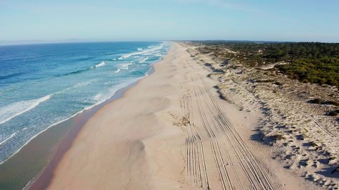 BEACH Portugal Praia do Pego - aerial shot of an empty lonely sandy beach at the Atlantic Ocean in the soft morning light – drone is flying high over tracks on the beach further out to the ocean