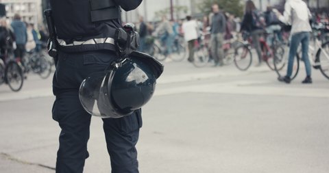 Police officer in full protection riot gear with helmet gun and baton guarding demonstrations on bicycles protest for protection of nature in Europe during pandemic