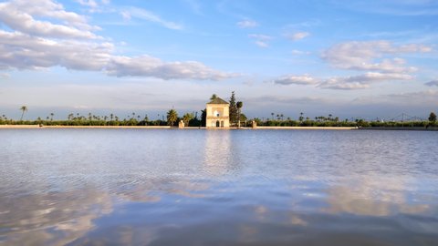Moving clouds with rewlection in water lake time lapse 4K. Morocco - Marrakech Menara gardens view