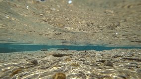 A small wave rolls over pebbles. Underwater shooting