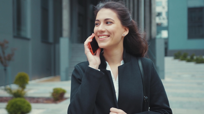 Business young attractive woman walking out of office corporate answering smartphone call talking with a friend outdoors. Beautiful people. Urban lifestyle. Communication. | Shutterstock HD Video #1053503318