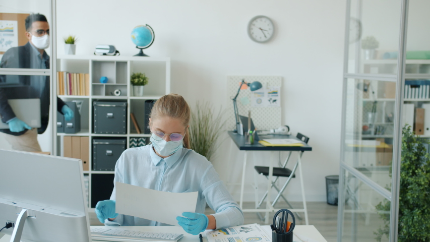 Arab man in mask and gloves is leaving office doing elbow high-five with Caucasian woman colleague during corona virus epidemic. Quarantine and work concept. | Shutterstock HD Video #1053509078