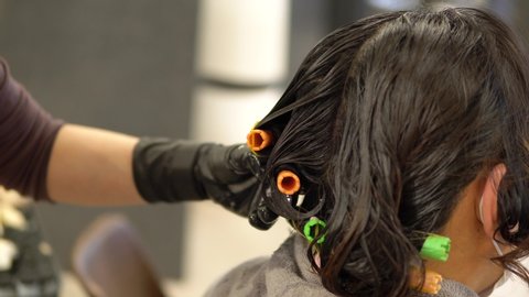 Hairstylist Putting Rubber Band To Perming Curler Rods On A Woman's Hair - closeup shot