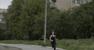 Athletic girl with dark hair in a gray tracksuit on a sports maidanchik runs, slow motion video