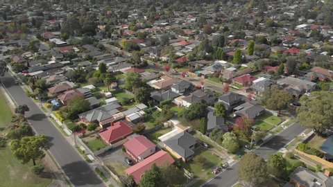Aerial shot angled downing along residential streets in a suburban landscape with lots of houses.