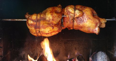 chicken roasting on a spit in garden grill with open fire