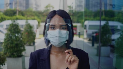 Asian young business woman wearing face shield and mask for healthcare which is required for doctor and general public to prevent COVID-19.