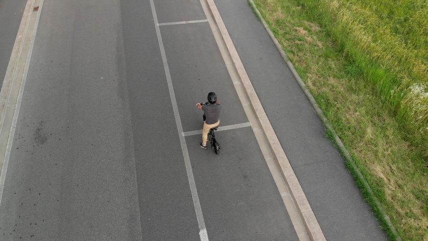 Aerial shot : Man rides his foldable electric bike on the street to go to work or uses it in his leisure. Bike commuter concept