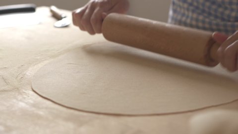 Slow motion process of homemade vegan farfalle pasta with durum wheat flour. The cook uses a rolling pin to stretch the dough, traditional Italian pasta - Woman cooks the food in the kitchen