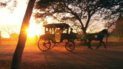 Retro transport in Burma, Bagan. Vintage horse wagon at sunset with shining sun and warm sun rays through trees and cart windows. Countryside of Myanmar