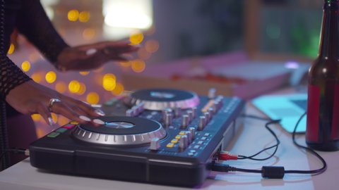  Slowmo mid-section of hands of unrecognizable female DJ using controller and mixing music at party