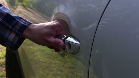 A young girl opens the door of her car. Close-up hands of a young girl open the car door.