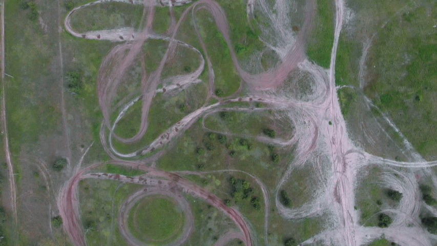 Top view of empty professional motorcycle motocross racetrack with enclosed manmade dirt circuits with steep obstacles. Drone shot of motopark surrounded by trees