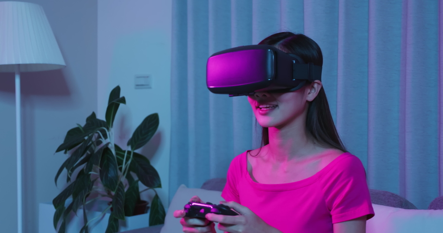 asian woman wears vr glasses with gamepad and win video games happily in the evening at home