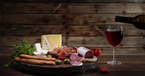 Antipasto of meat and cheese with a glass of wine. On wooden background.
