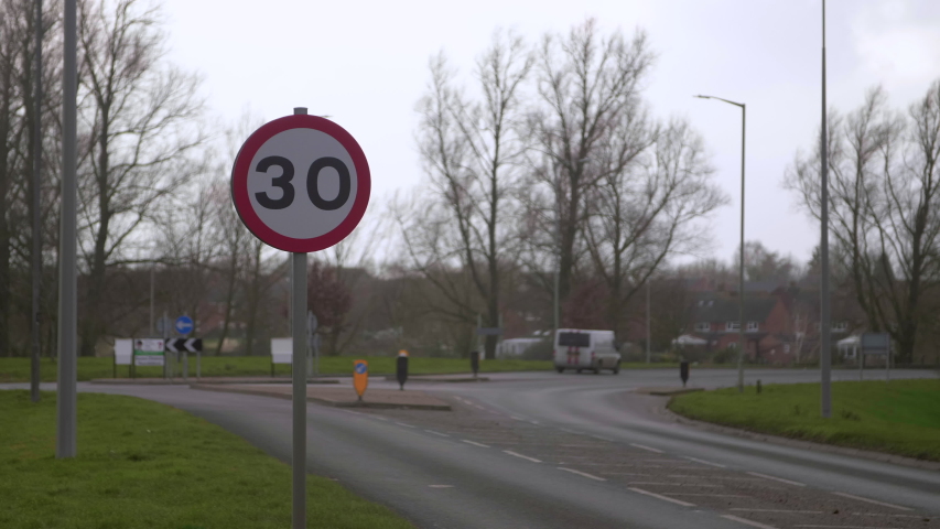 Speed limit sign with traffic passing in the background in England. Royalty-Free Stock Footage #1053552008