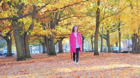Happy beautiful woman walking in fall park, trees with autumn leaves