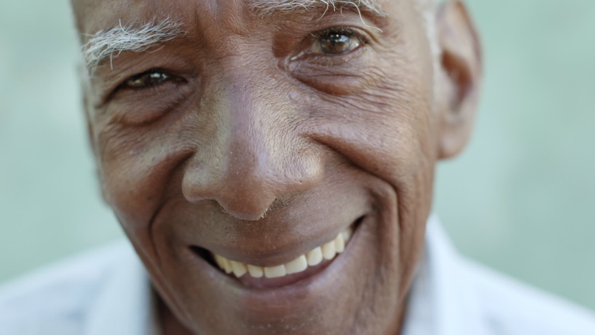 Portrait of elderly hispanic man smiling on bench in public city park. Happy black senior people looking at camera, senior having fun in leisure time. Tilt shot Royalty-Free Stock Footage #1053555170