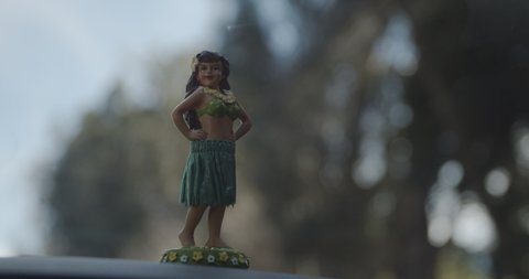 Vintage hula girl dash ornament swaying as car drives on a road trip