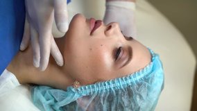 4k vertical video doctor touches and rotates girl face on consultation. Inspection before plastic surgery. Cosmetic rejuvenating facial treatment. Lips augmentation, wrinkle removal