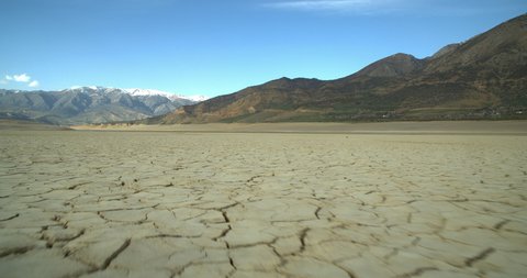 View of a dried-up lake or river in a mountainous area due to an environmental problem. Cracked soil due to global warming. 4K frames