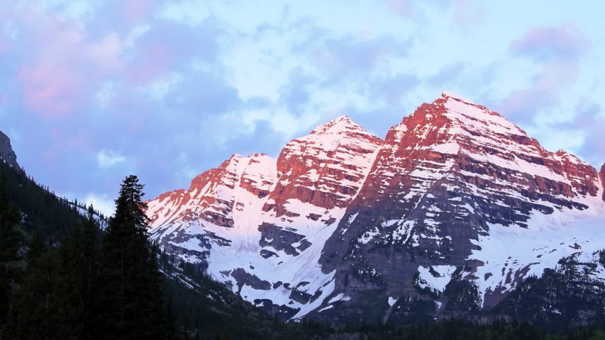 Maroon Bells closeup peak seamless loop cinemagraph with pink red sunrise light in Aspen, Colorado rocky mountain view and snow in summer trees clouds moving