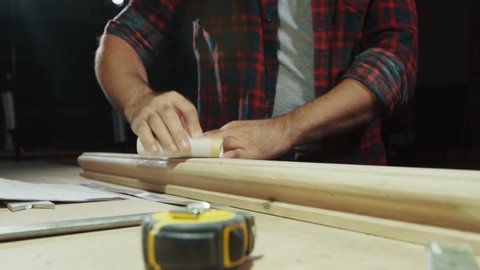Close-up hand rubs a wooden product with sandpaper, slow motion