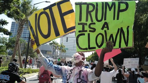 Miami Downtown, FL, USA - MAY 31, 2020: Black man with posters against US President Donald Trump. Trump is a clown it said. Demonstration against racism and politics, elections, vote.