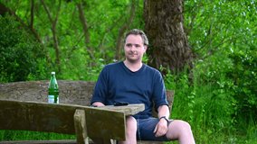 a man is sitting on a wooden bench in nature enjoying the summer day and using his smart watch
 - Powered by Shutterstock - Get 15% off with code: PIKWIZARD15