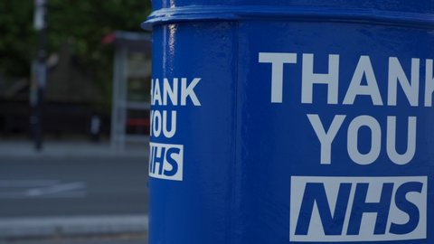 UK, London, 1/6/2020 - A close up pan shot of the back of a Blue Thank you NHS Letterbox with a red London bus driving past
