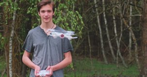 Boy lifts the drone using the remote control. Teenager launches a drone in the open air. Young man plays with a drone in nature. White boy learns to fly a drone in a Park. Slow motion video.