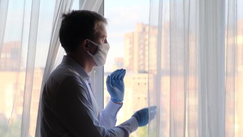 A man applauds doctors looking out the window at home. Coronavirus pandemic and doctors' hard work